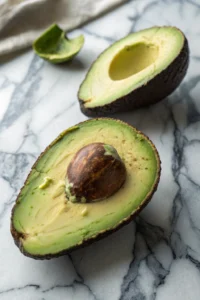 Cut avocado displayed on marble surface showing perfect diagonal scoring pattern for easy scooping